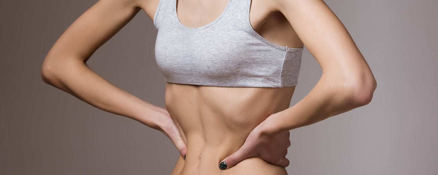 An emaciated woman with anorexia nervosa grasps her torso.