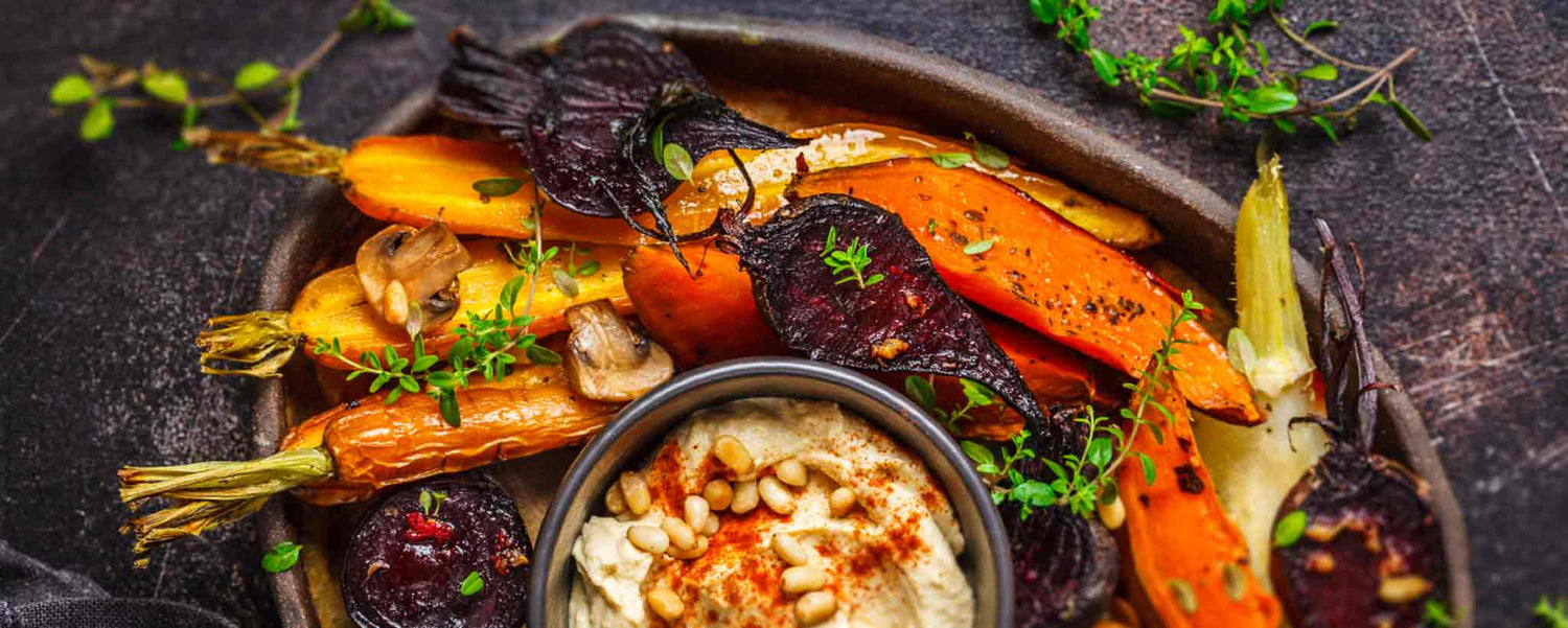 A platter of roasted root vegetables on a wooden table.