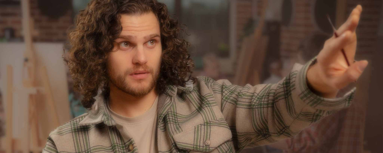 An at student in a classroom extends his arm.