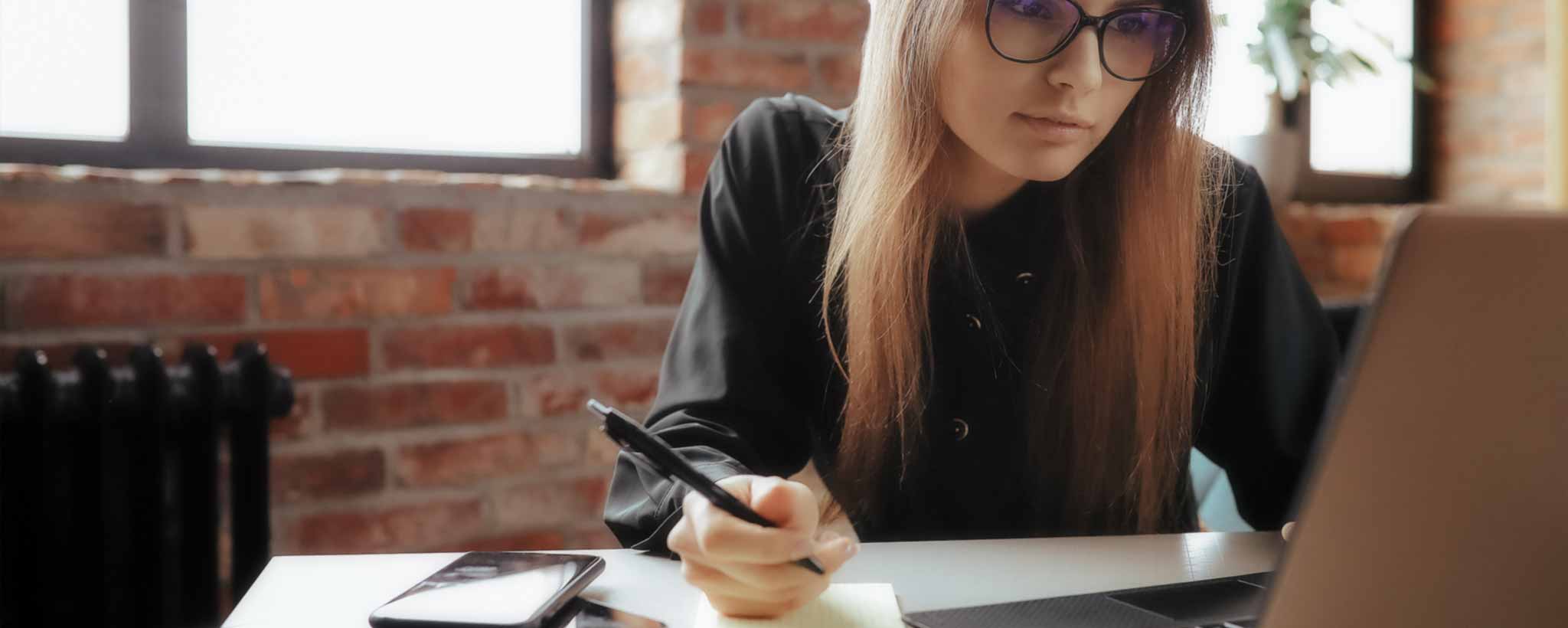 'Female writing on paper and computer'