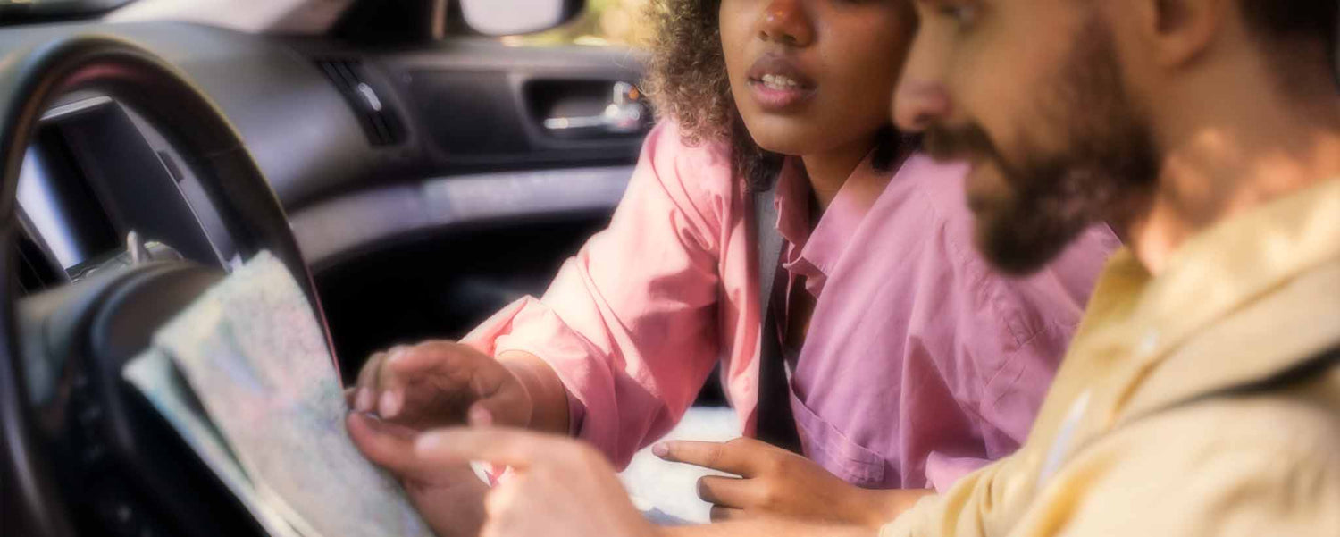 A biracial couple sits in the car to map their destination.