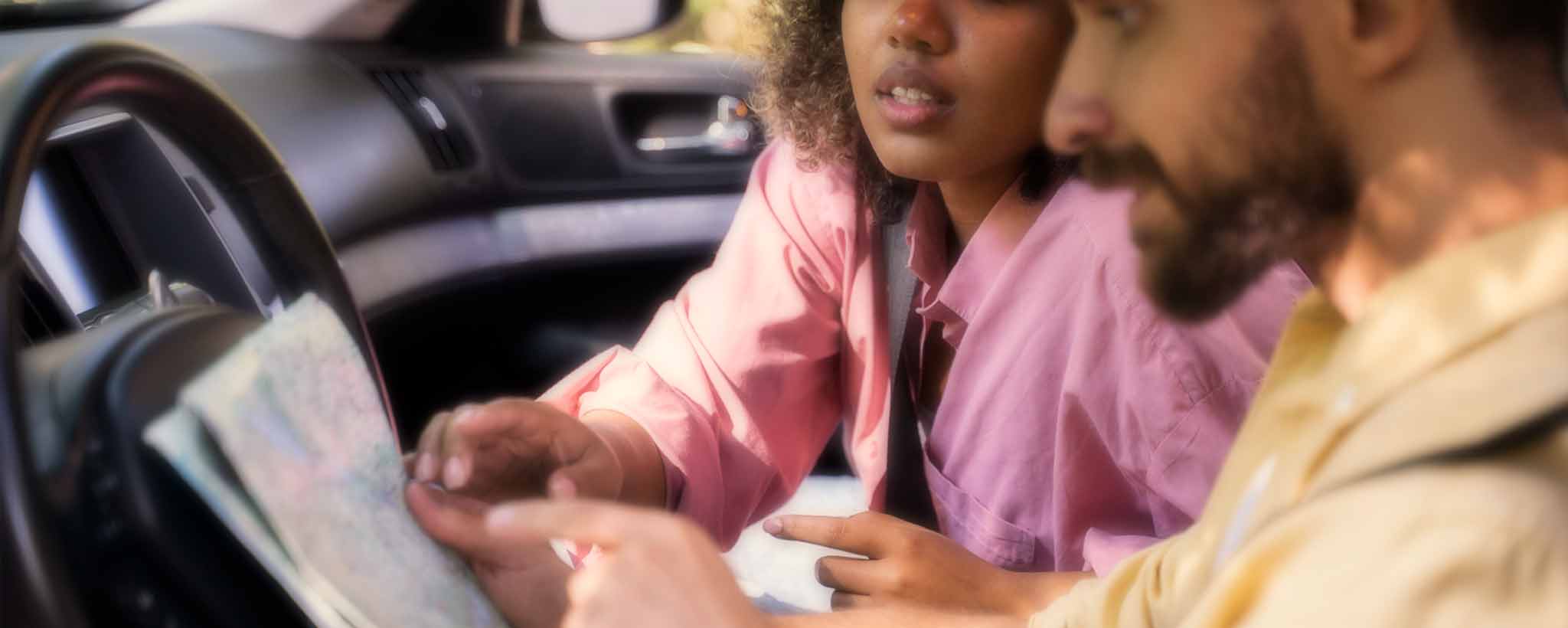 'A biracial couple sits in the car to map their destination.'