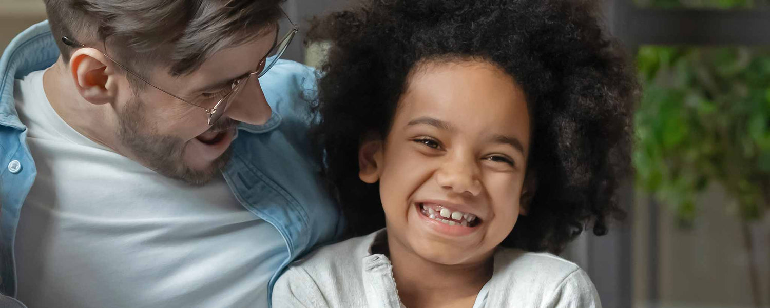 A Caucasian father smiles with his biracial daughter.