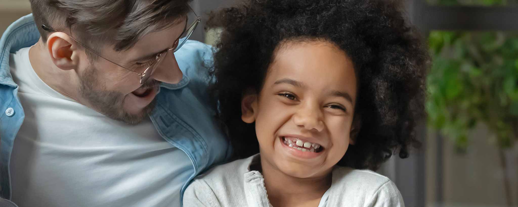 'A Caucasian father smiles with his biracial daughter.'