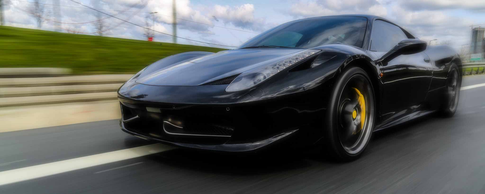 'A black sports car speeding on highway.'