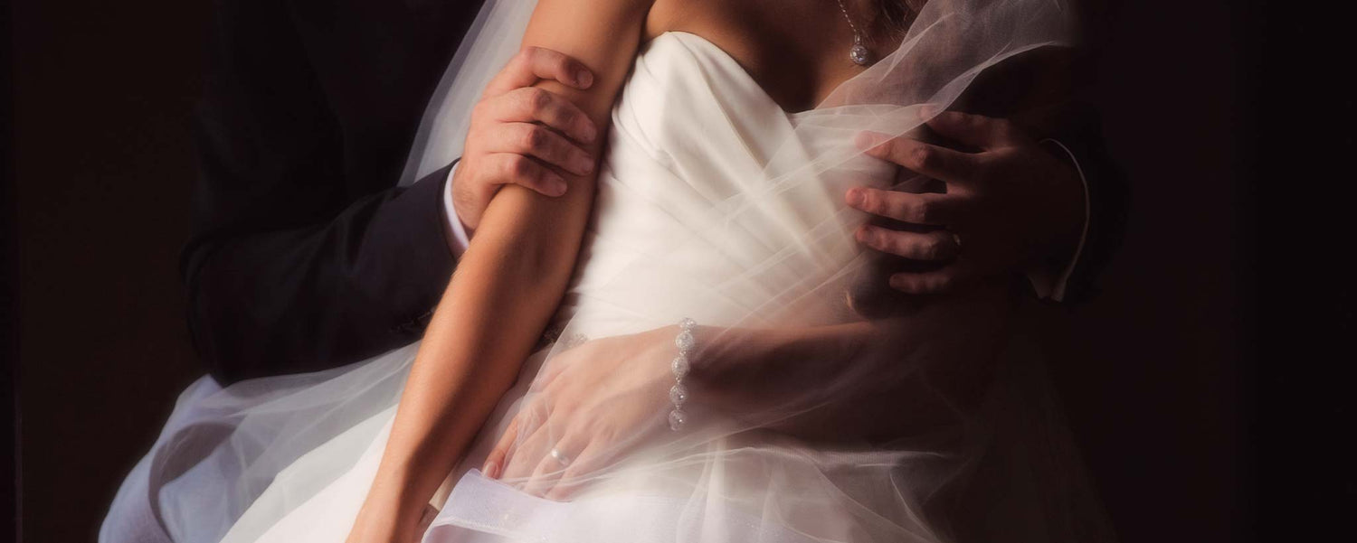 A groom hugs his bride in a dark room.