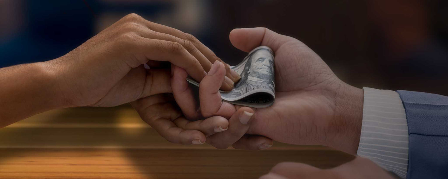 Two hands exchange cash at a table.