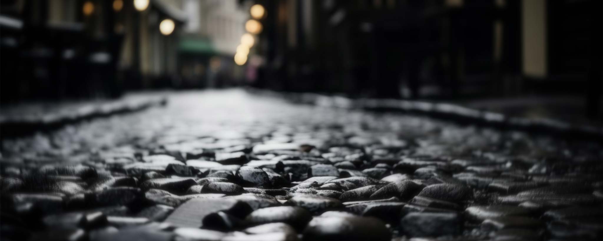 'A dark cobblestone road lit by dim streetlights.'