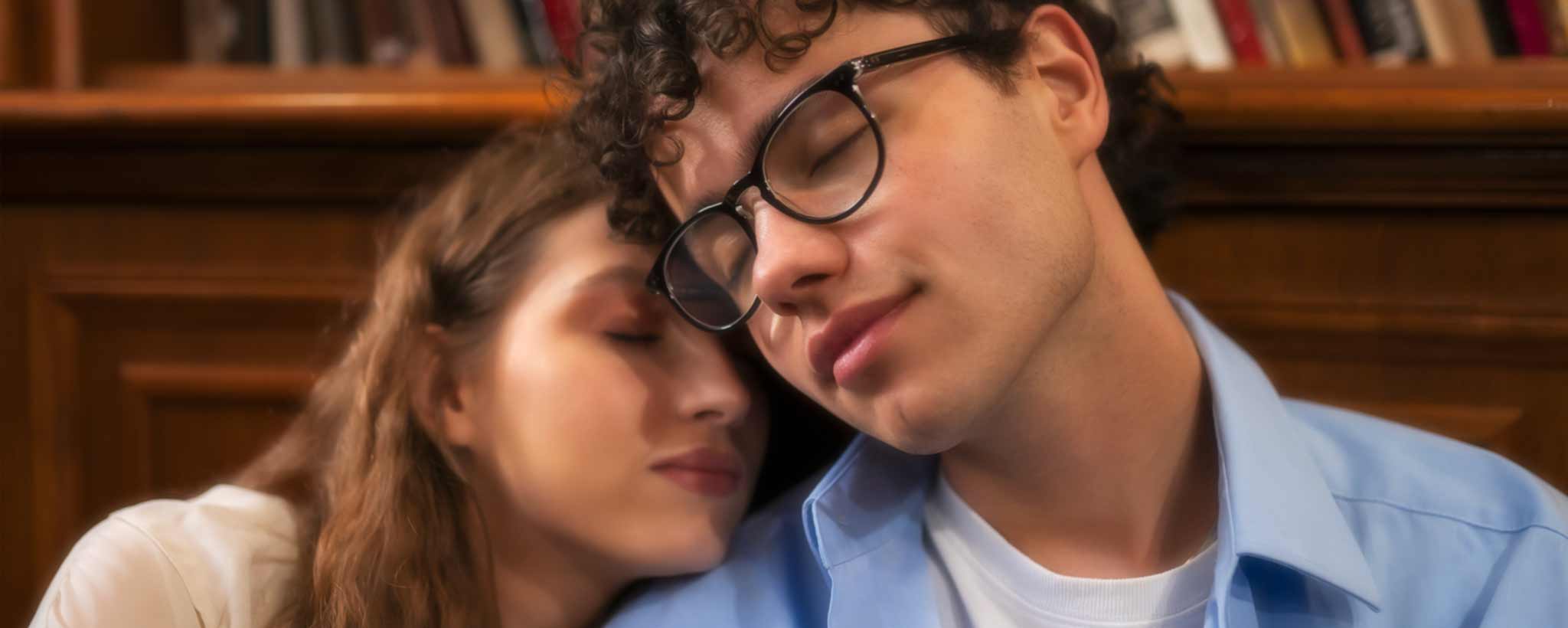 'A college couple lean on each other in a college library.'
