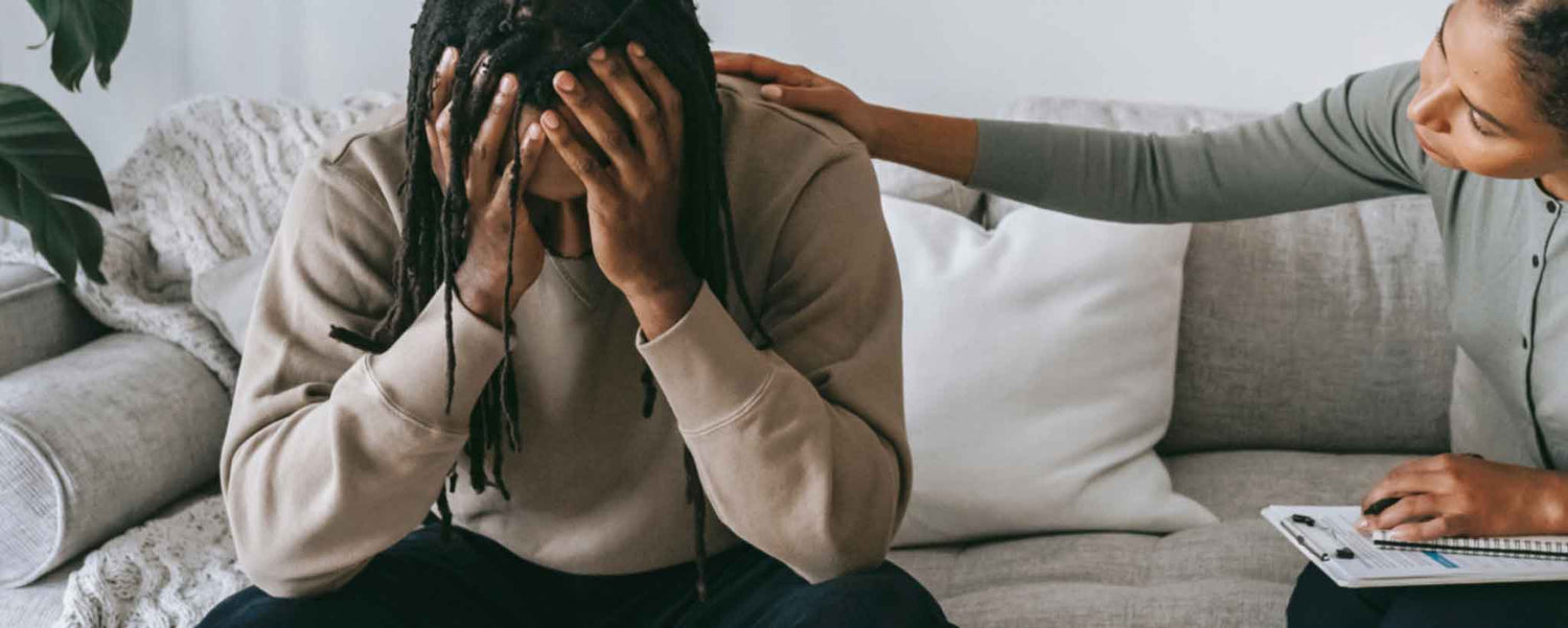A therapist comforts a black male patient.