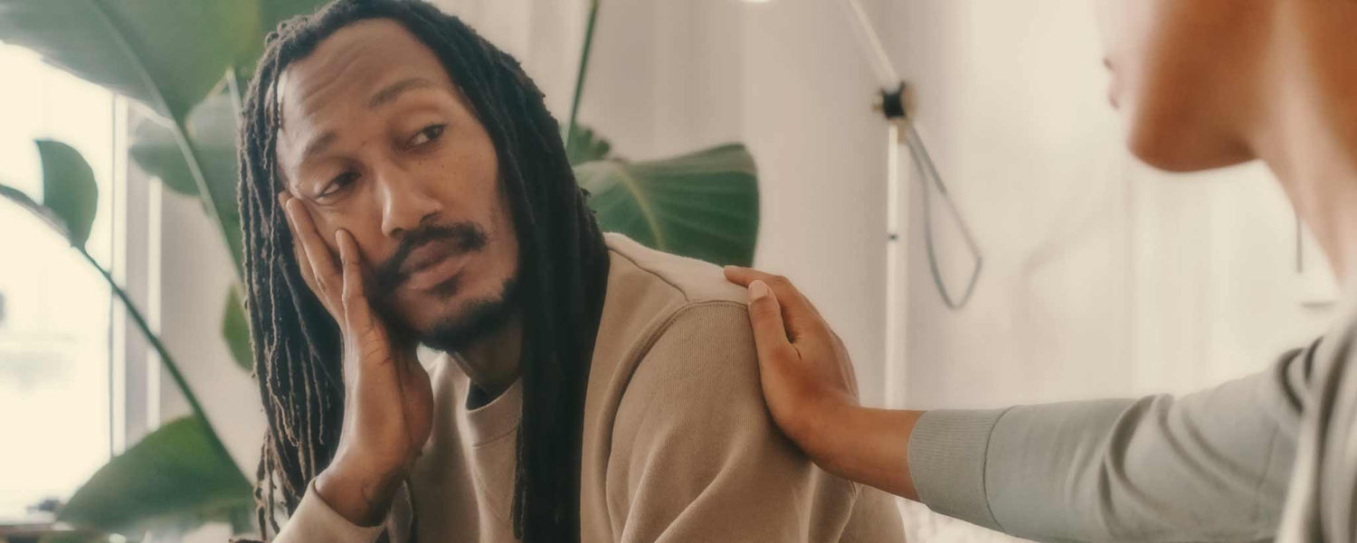 A therapist rests her hand on a patient's shoulder during a therapy session.