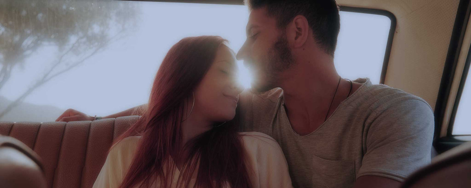 A romantic young couple in the backseat of a car.