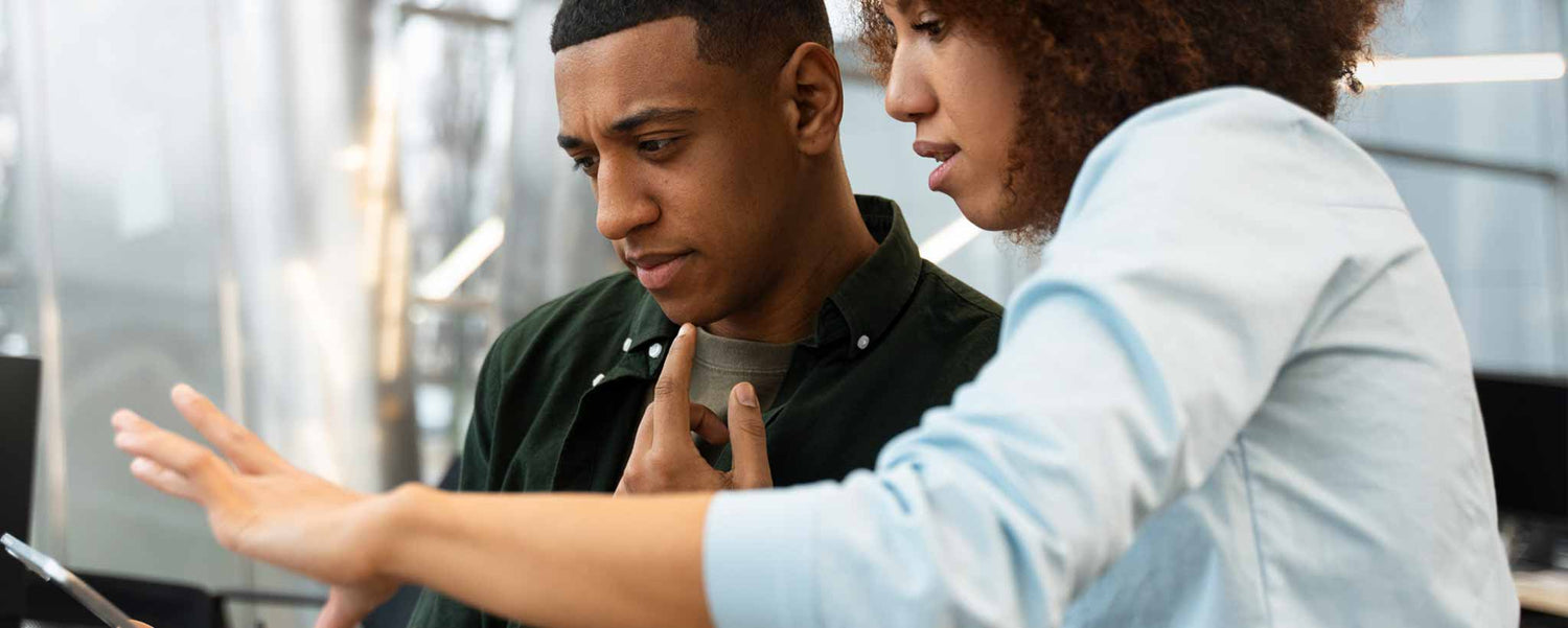 Two people working together on a computer in an office setting.