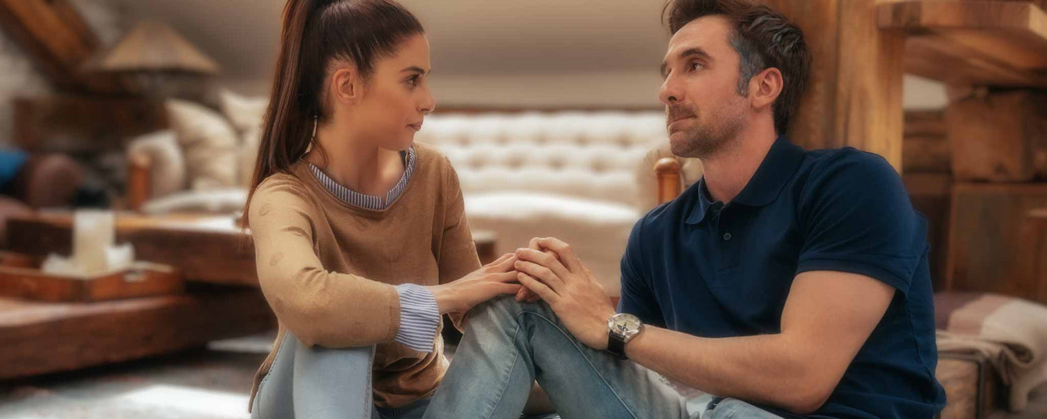A couple converse on the floor of a home.