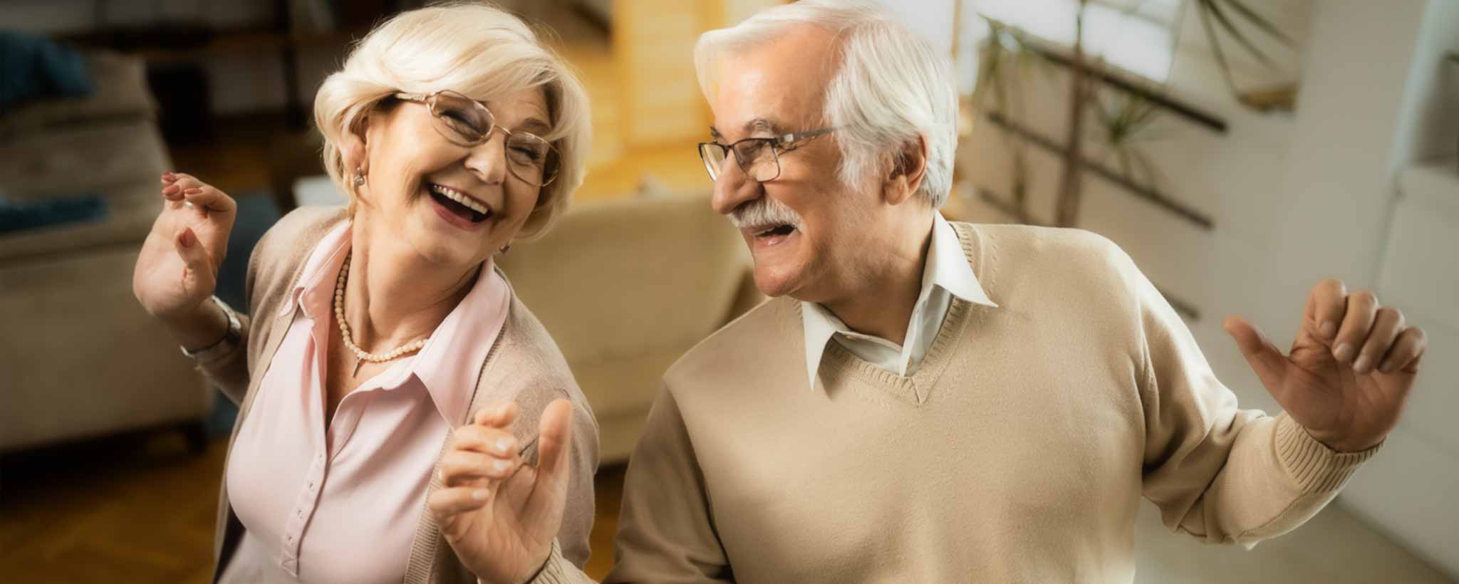 'Senior couple dances in living room'