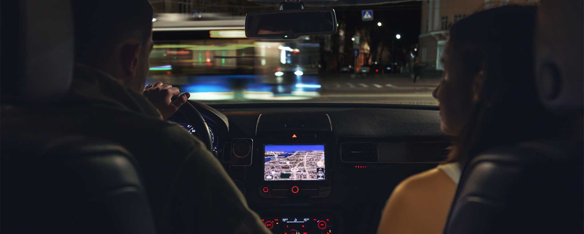 'A couple is seated in the front seat of a car at night. (ai)'