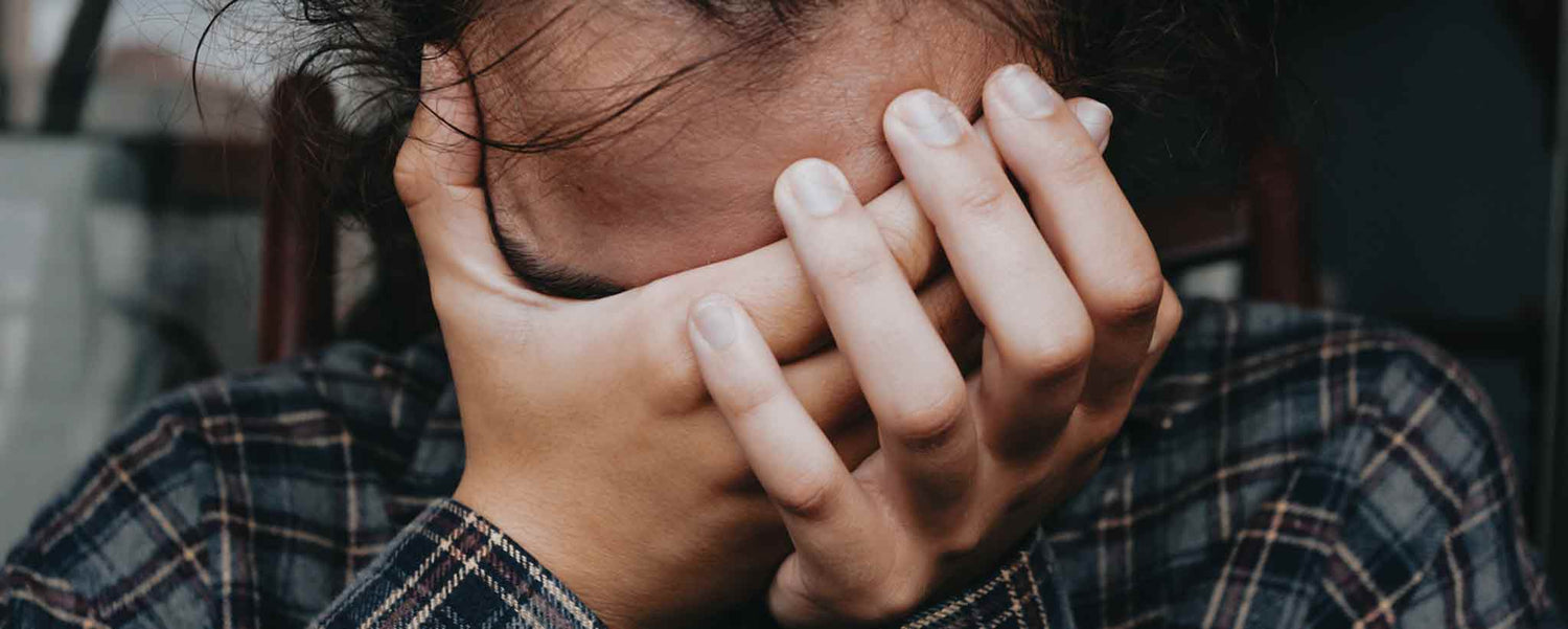 A male covers his face with his hands.