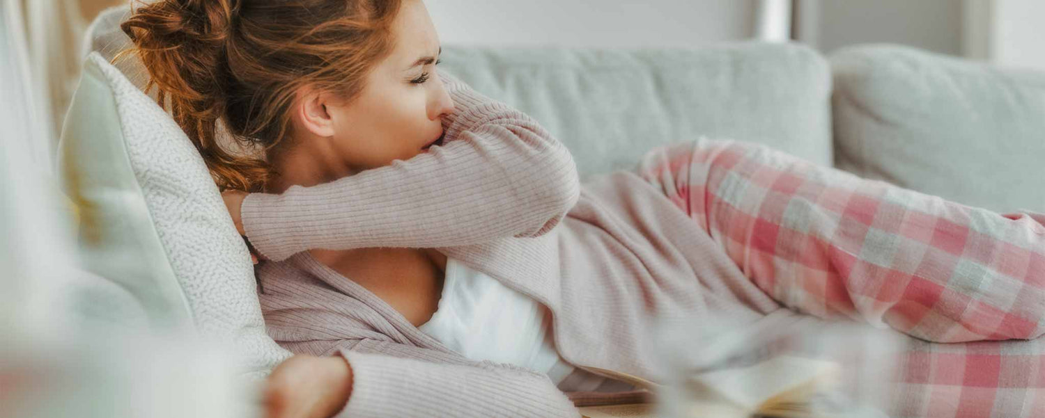 Female on sofa coughing into elbow