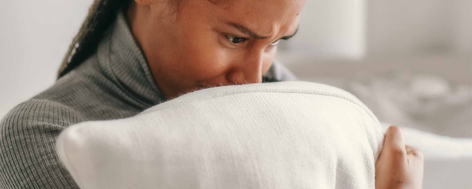 A lonely female cries into her pillow.