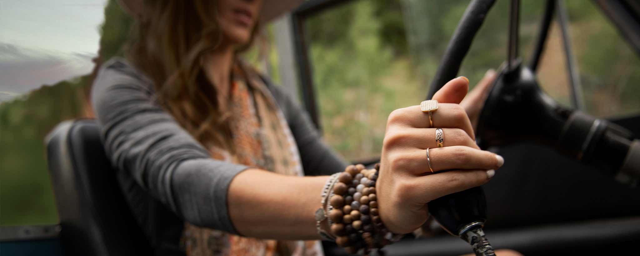 'A female drives a jeep along a narrow mountain road.'