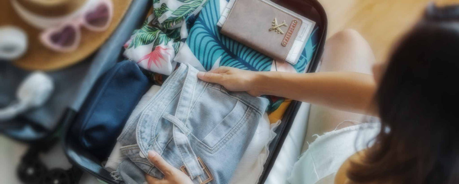 A female packs a suitcase.