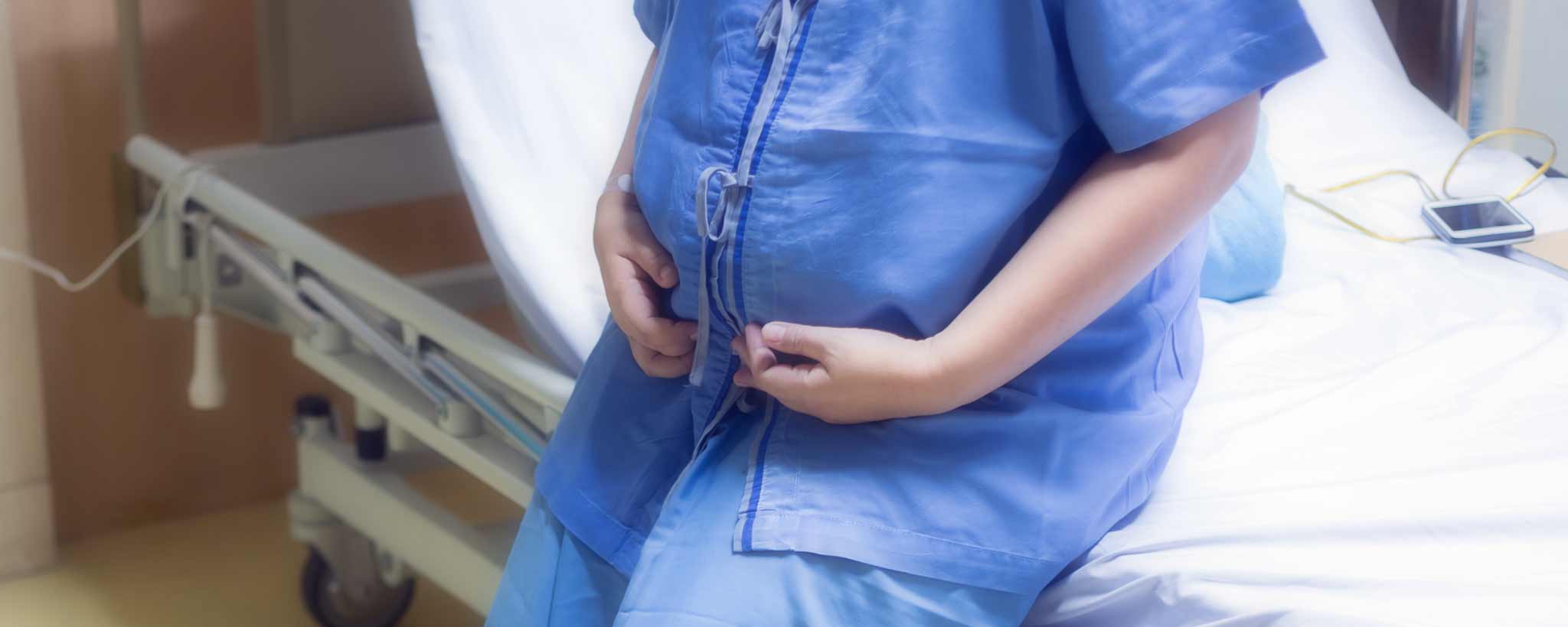 'Pregnant patient seated on hospital bed'