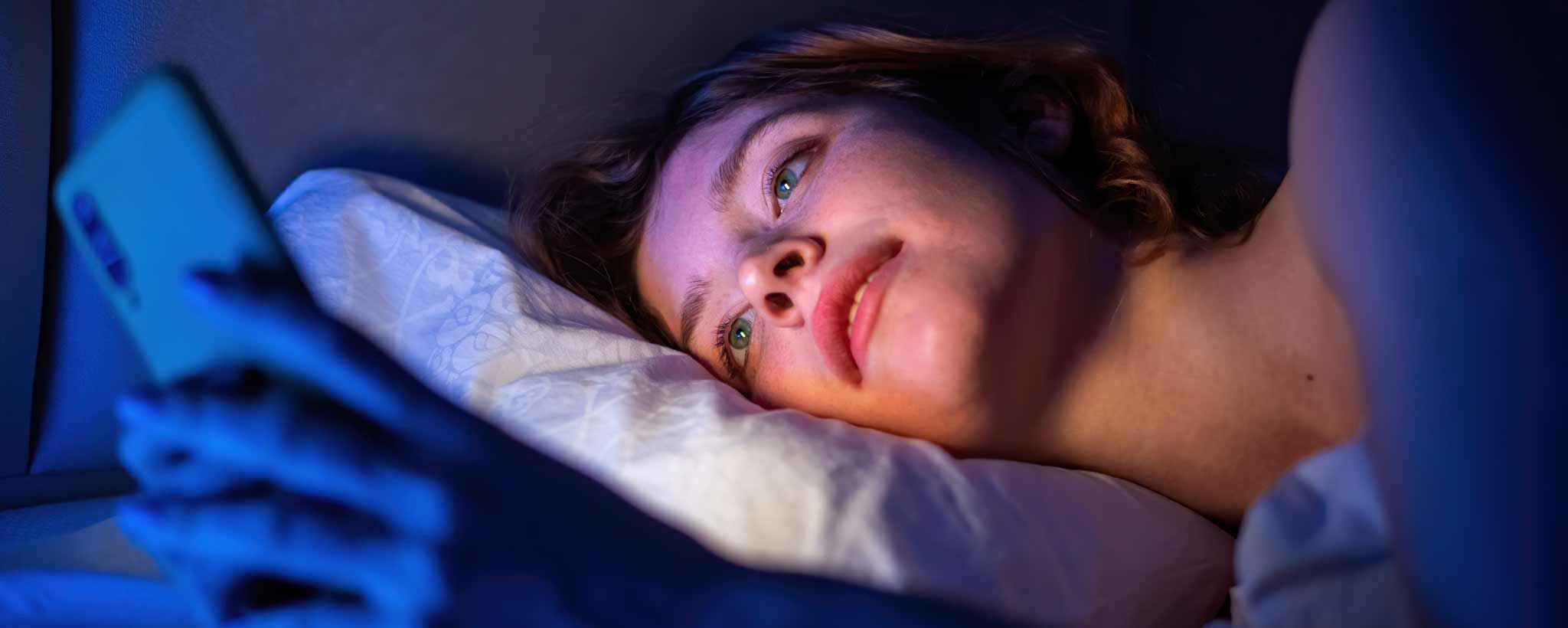 'Female lying in bed with smartphone'
