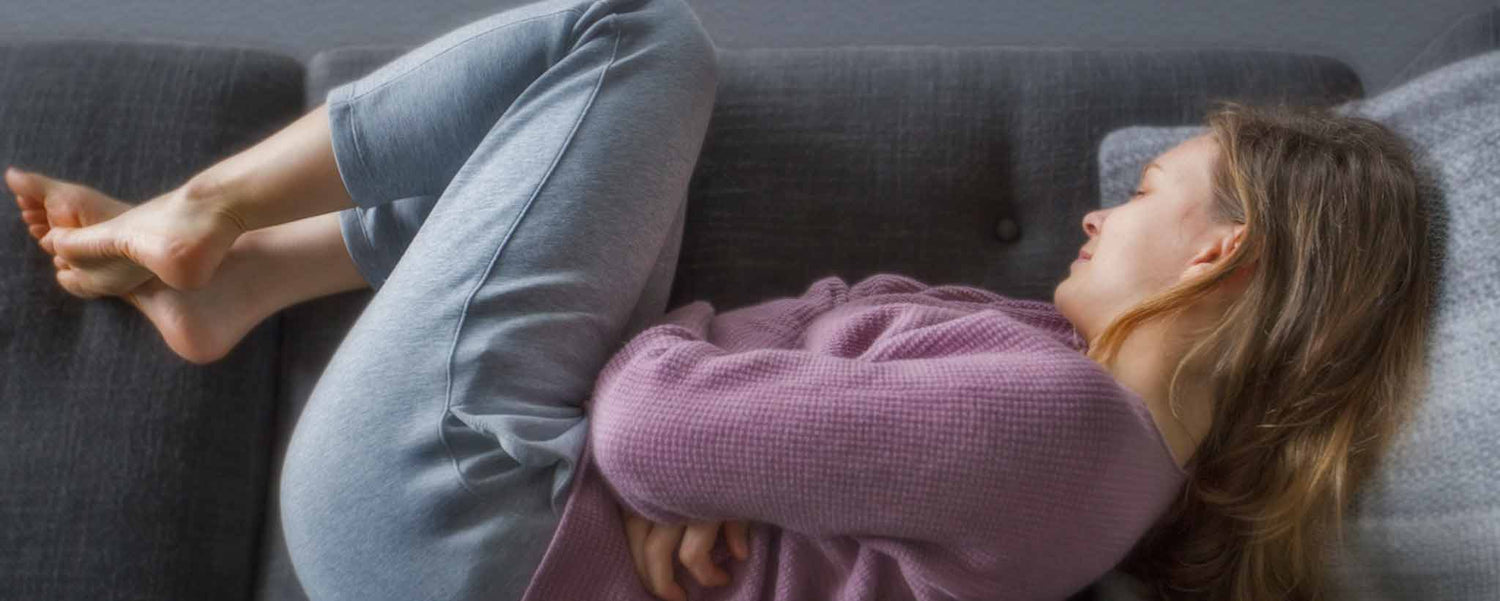 Female holding stomach on sofa