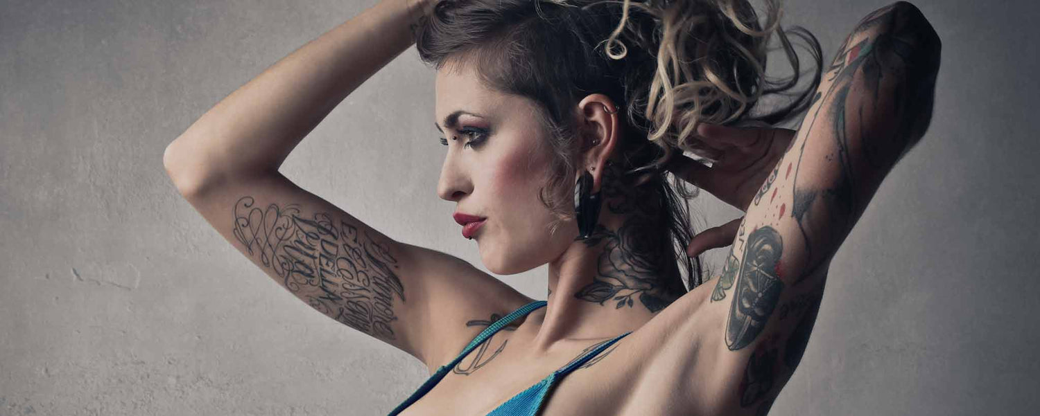 Female holds up her arms with tattoos.