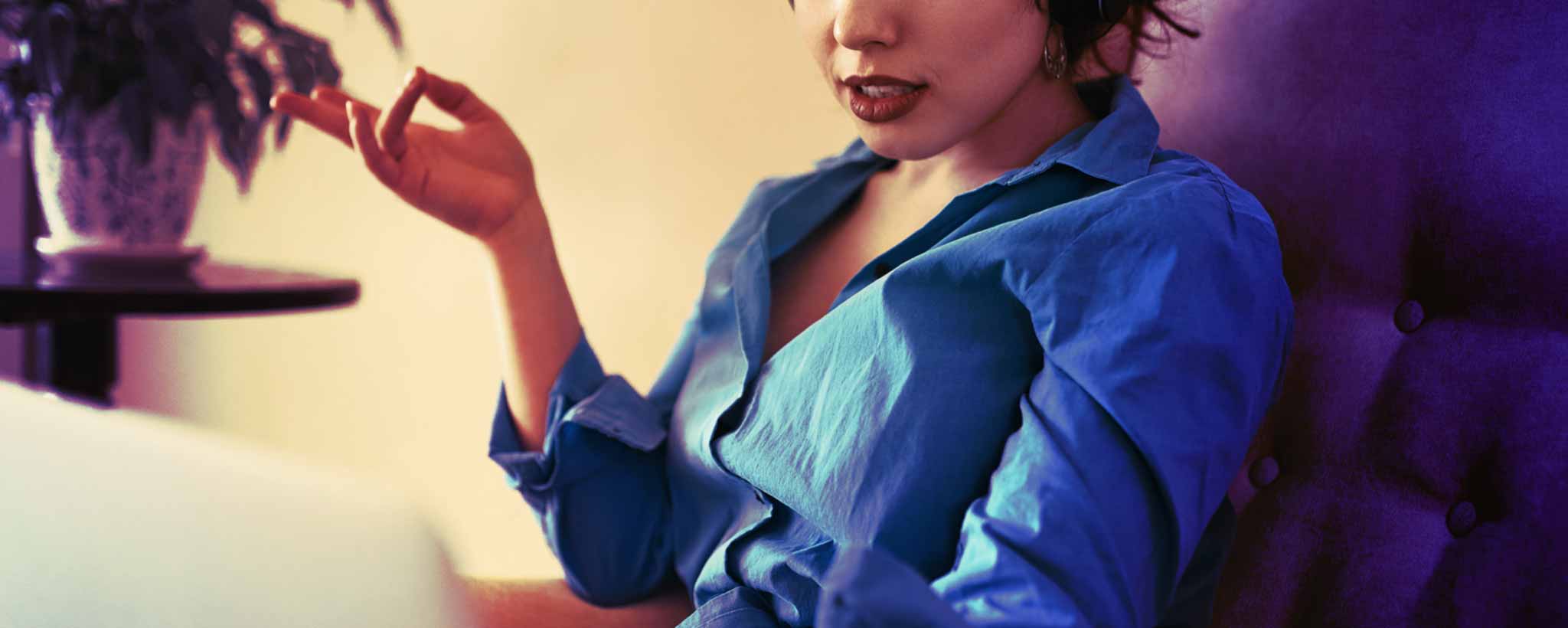 'A seated lady gestures while talking during a video shat.'