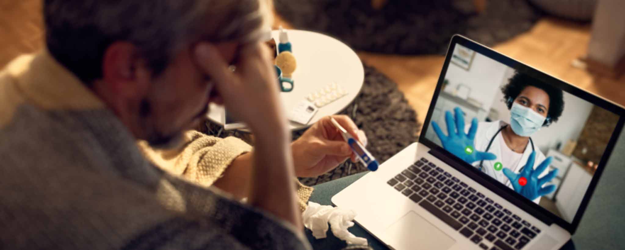 'Patient holding thermometer during medical videoconference'