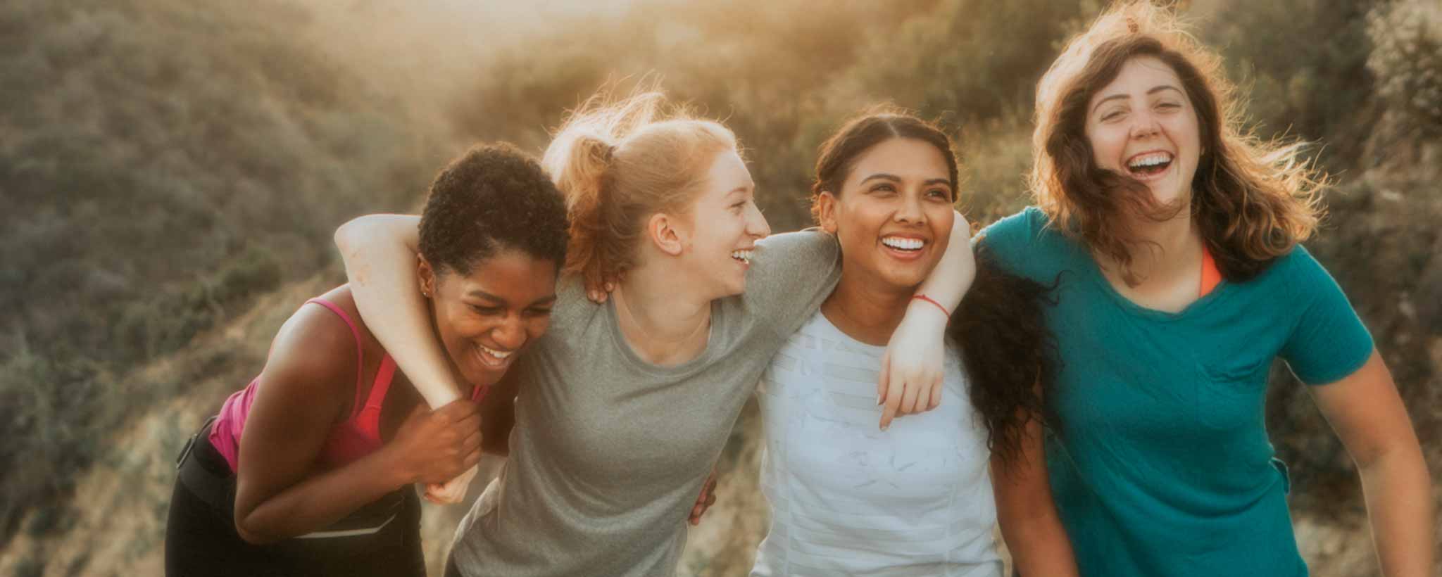 'Four smiling women hiking in hills'