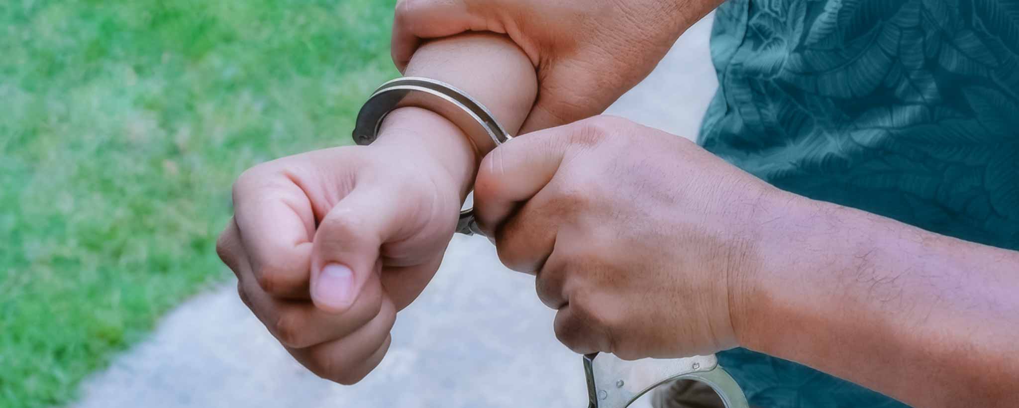 'An officer snaps handcuffs on man's wrist.'