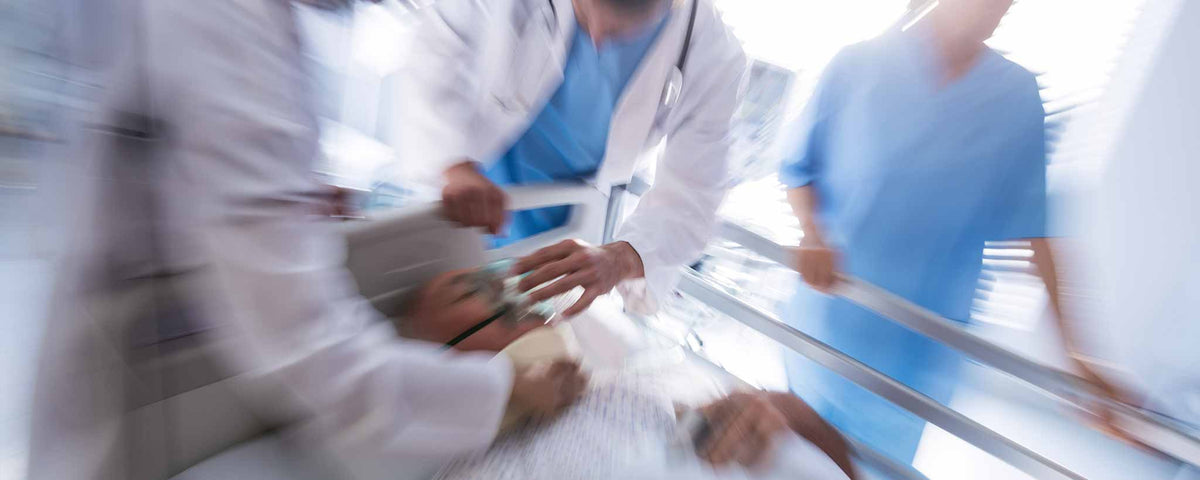 'Medics rush an emergency patient through the hospital hallway.'