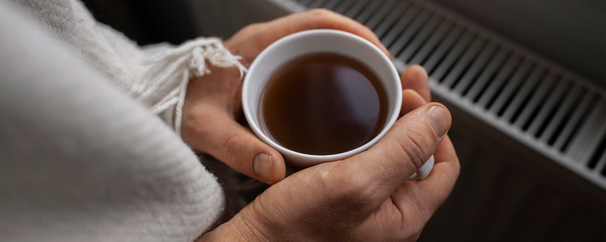 'Man warming hands with hot beverage'