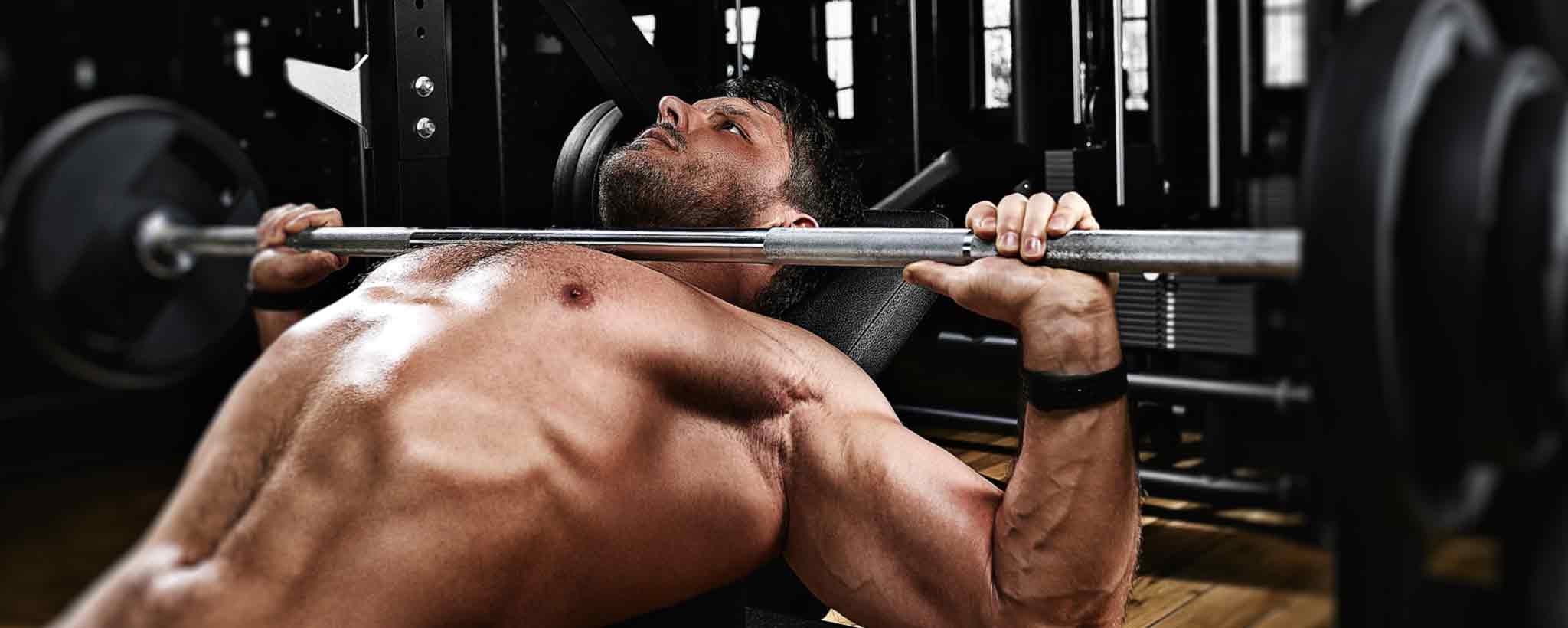 'A strong man bench presses in a gym.'