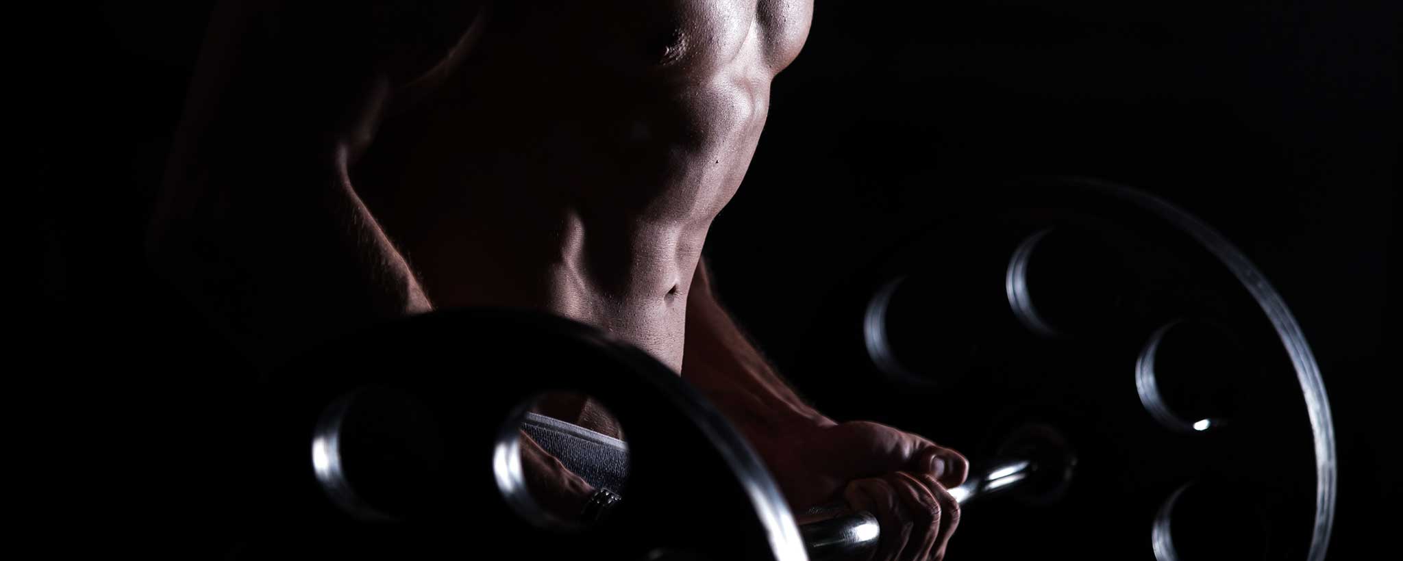 'Male fitness trainer lifts a barbell.'