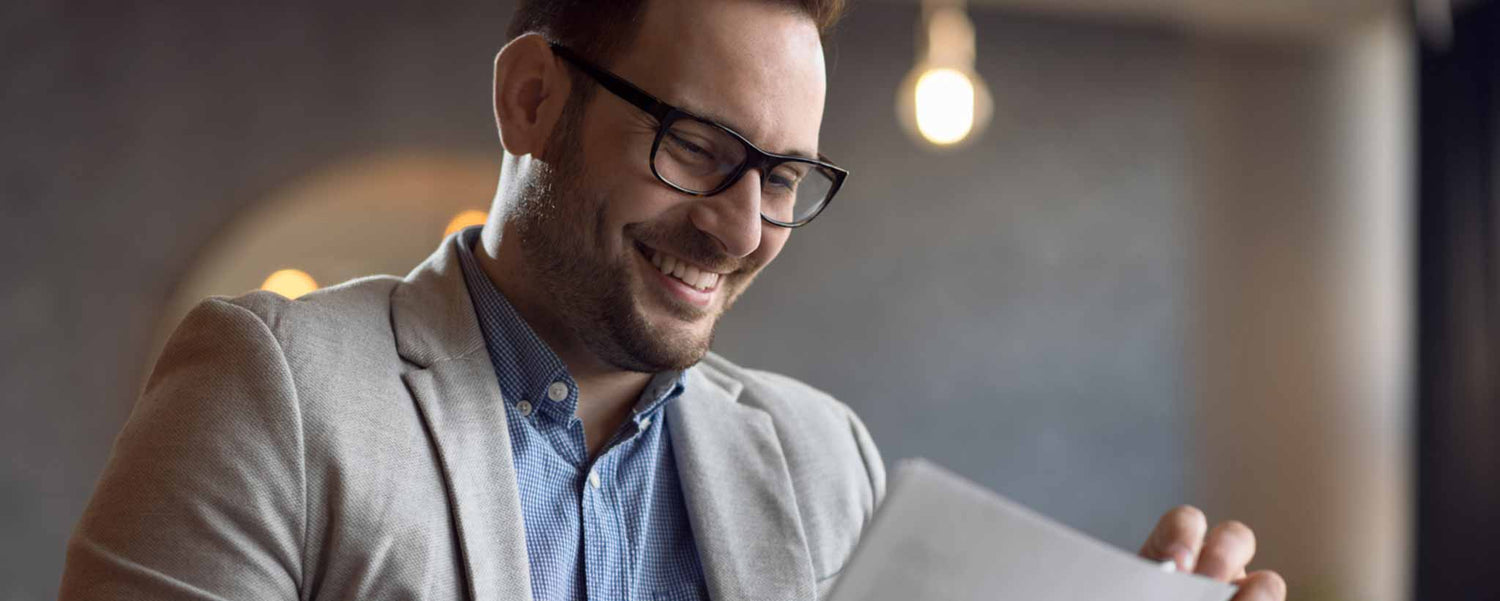 A happy bearded man reading papers.