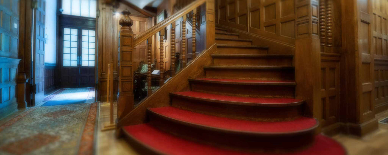 A red-carpeted staircase in a mansion.