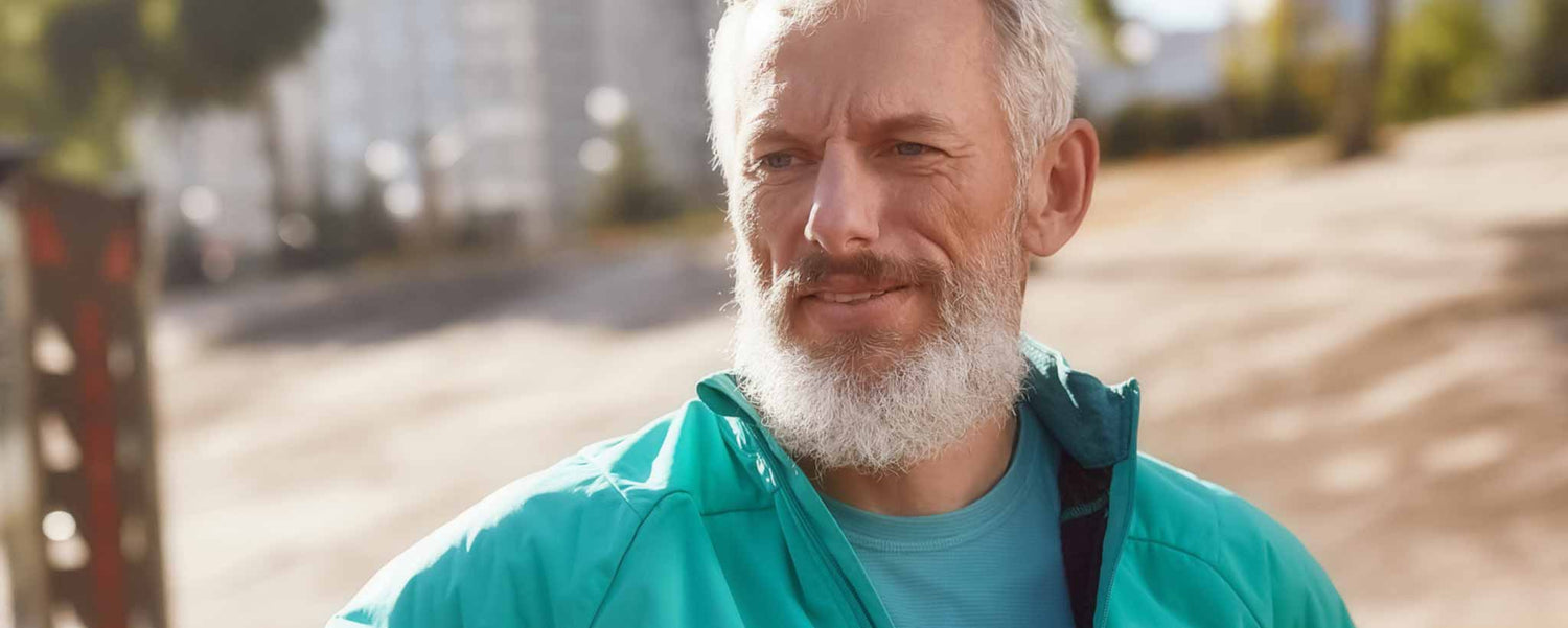 A senior bearded man walks during a sunny day to keep fit.