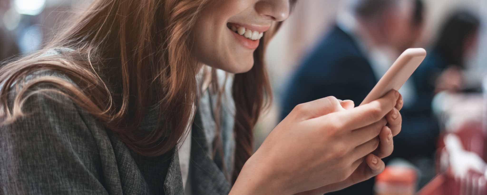 'A smiling lady viewing her phone.'