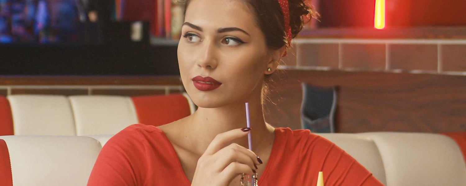 A beautiful blonde drinking malt in a diner.