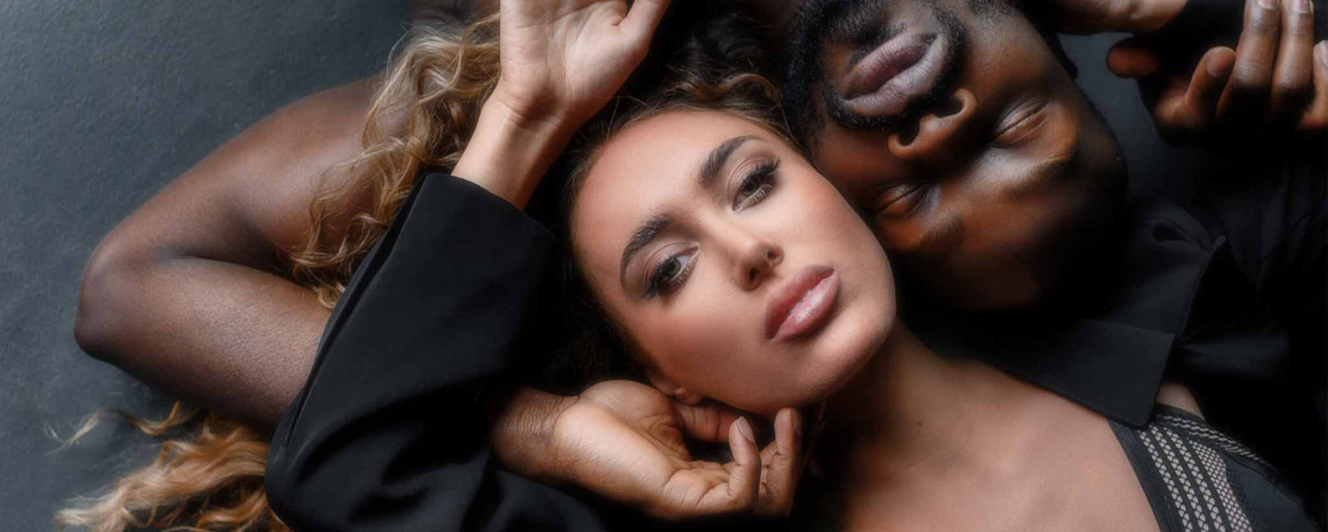 A romantic black couple lie entwined, heads together.