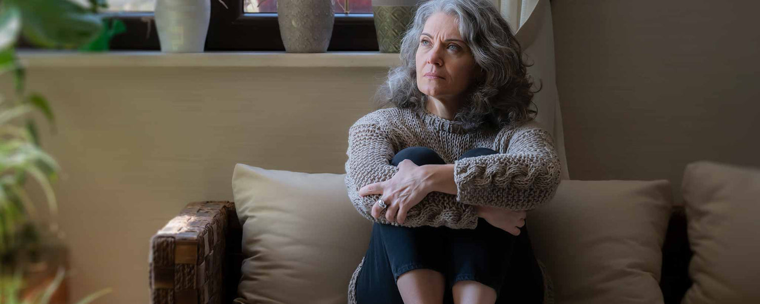 An elderly female siting on a couch in a living room.