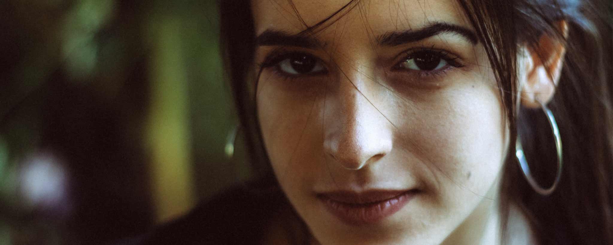 'Close-up of a person with hoop earrings against a blurred background.'