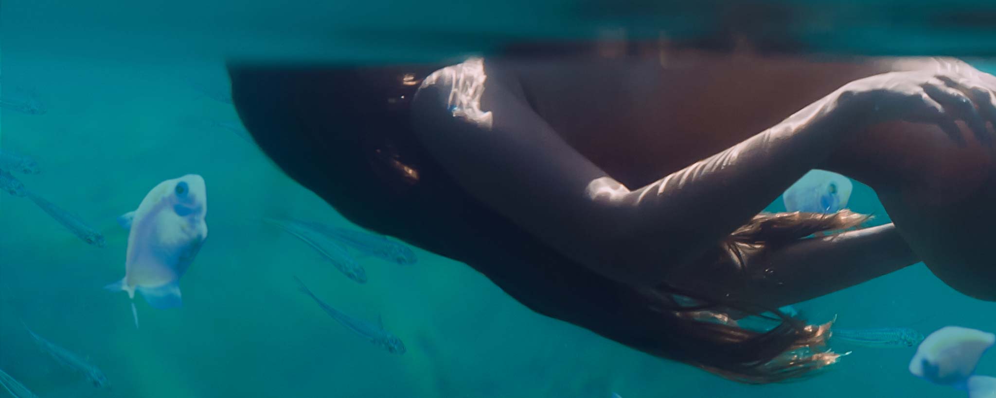 'Underwater profile view of a female skinny dipper floating on the surface.'