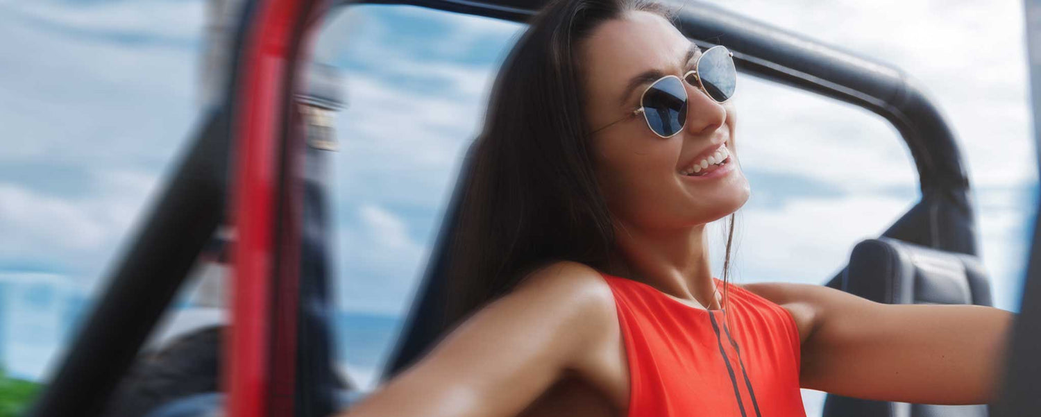 Woman wearing sunglasses smiles in jeep