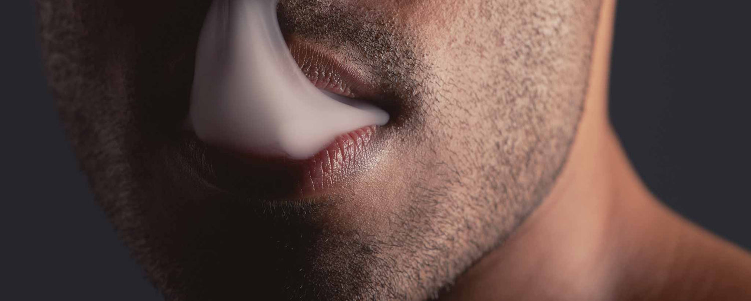 Vape smoke rises from a man's mouth.