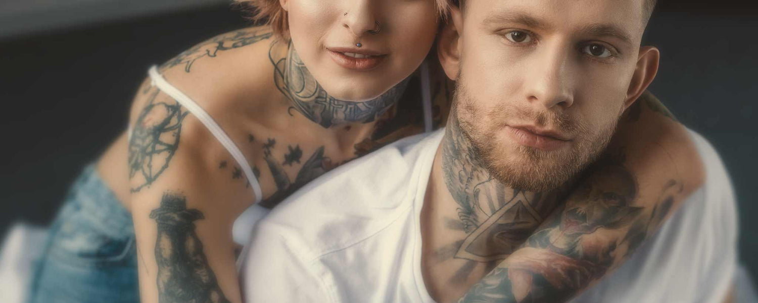 A tattooed couple hug.