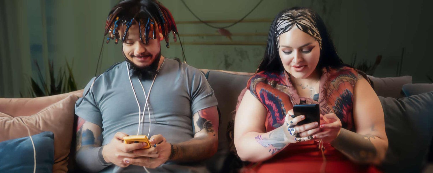 A tattooed couple using digital devices on the sofa. (ai)